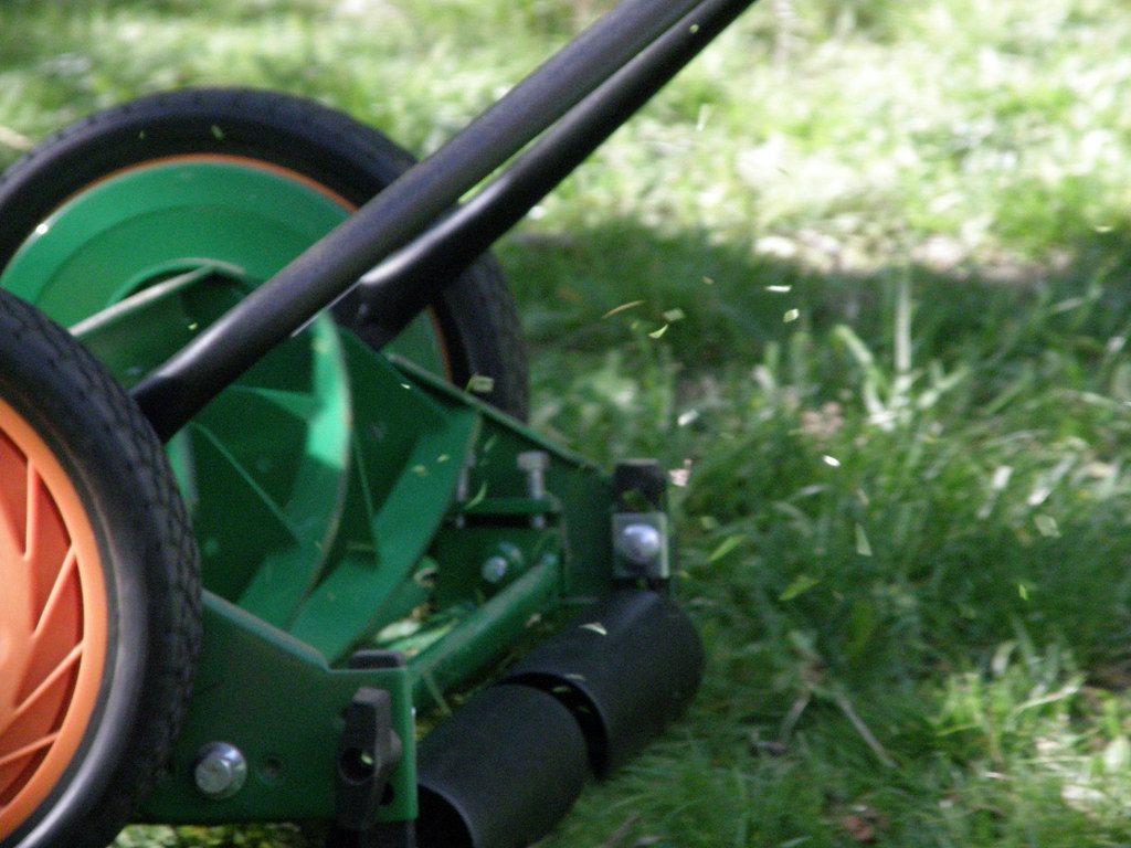 Photo by Dan4th on Flickr (CC BY 2.0) A manual push reel mower cutting grass, clippings flying off the reel